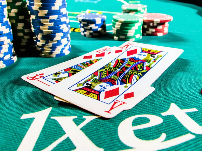 Bàn chơi Poker tại 1xBet với các lá bài và chip cược, tập trung vào tay bài mạnh và biểu cảm của người chơi, tượng trưng cho trò chơi đấu trí đỉnh cao.